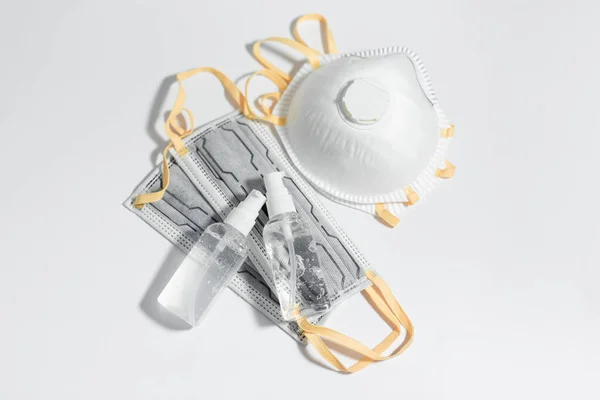 Beyaz masadaki antiseptik jel şişelerinin ve Coronavirüs 'e karşı solunum gribi maskelerinin üst görüntüsü..