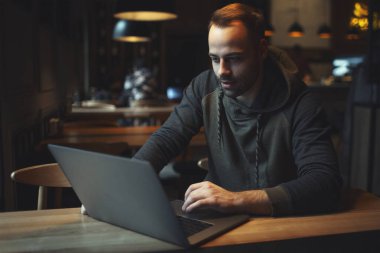Kafede dizüstü bilgisayarda çalışan, serbest çalışan neşeli genç adamın portresi..