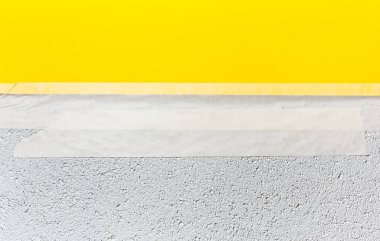 Beyaz duvarda viskiyle bantlanmış sarı kağıt..