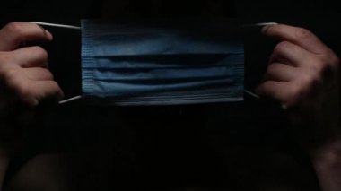 Siyah arka planda Coronavirus 'a karşı tıbbi grip maskesi takmış hasta bir gencin koyu yakın plan portresi..