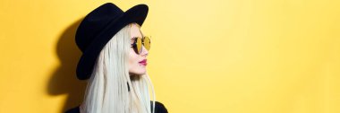 Panoramik profil portresi. Genç sarışın kız. Güneş gözlüğü takıyor ve siyah şapka takıyor..