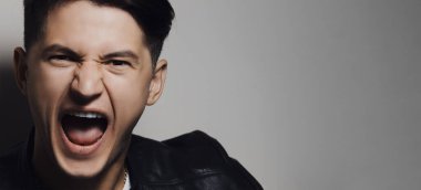 Arka planda çığlık atan genç adamın yakın çekim portresi. Fotokopi alanı olan gri arka plan..