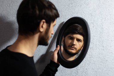 Aynaya bakan genç adamın dramatik portresi.