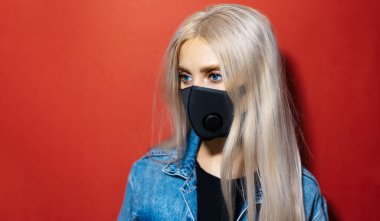 Solunum maskesi takan genç sarışının stüdyo portresi kırmızı renkli koronavirüse karşı fotokopi alanı ile.