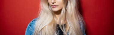 Kırmızı arka planda genç sarışın kızın panoramik yarı yüz portresi.