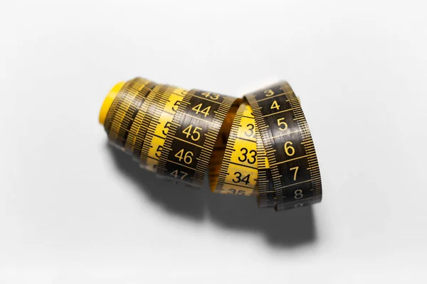 Close-up of black and yellow measuring tape isolated on white background with shadows.