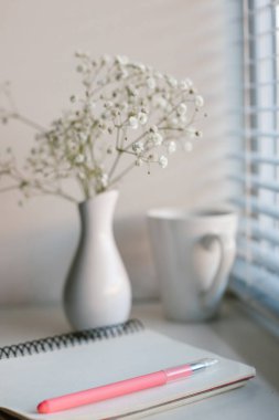İş yeri. Vazo ve defterde beyaz çiçekler. Boşluğu kopyala