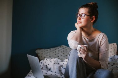 Evde, yatakta çalışan bir kadın. Kadın işi. Boşluğu kopyala