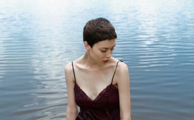 Girl with short hair on the background of water looking away clipart