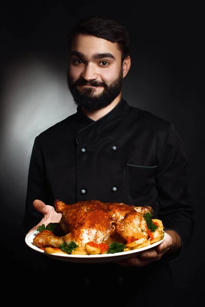Chef profissional com barba de uniforme preto com frango cozido nas mãos — Fotografia de Stock