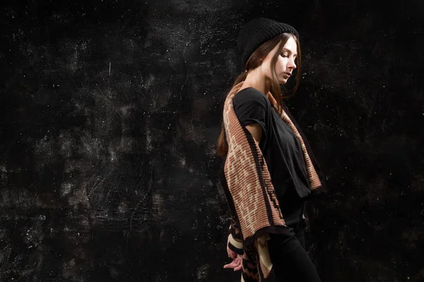 Jolie fille en vêtements à la mode sur un fond noir texturé mur — Photo