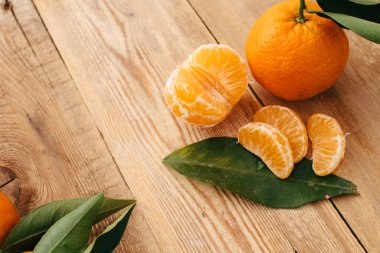 Ahşap arka planda yeşil yapraklı mandalinalar.