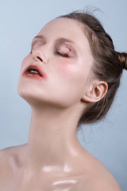 Duygusal olarak mavi bir arka plan üzerinde poz ıslak makyajlı kız