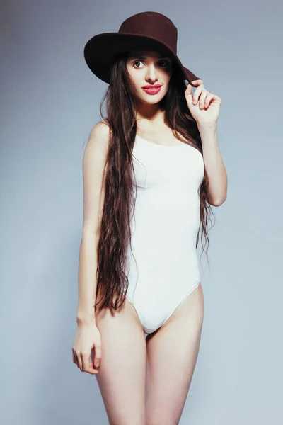 Vacker flicka med långt hår i en vit kropp kostym och hatt — Stockfoto