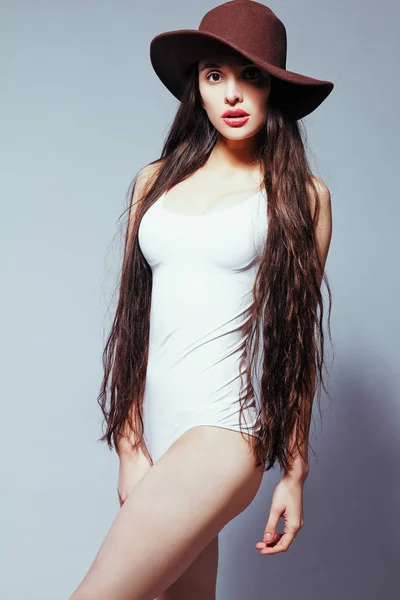 Beautiful girl with long hair in a white body suit and hat — Stock Photo, Image