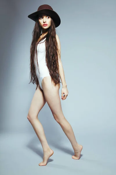 Menina bonita com cabelos longos em um terno corpo branco e chapéu — Fotografia de Stock