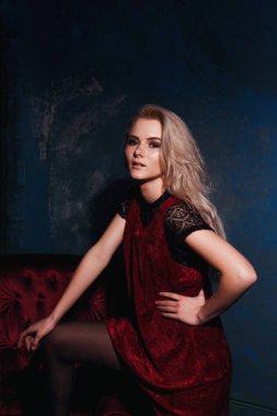 Bir sandalyede bir elbise ile poz güzel sarışın kız