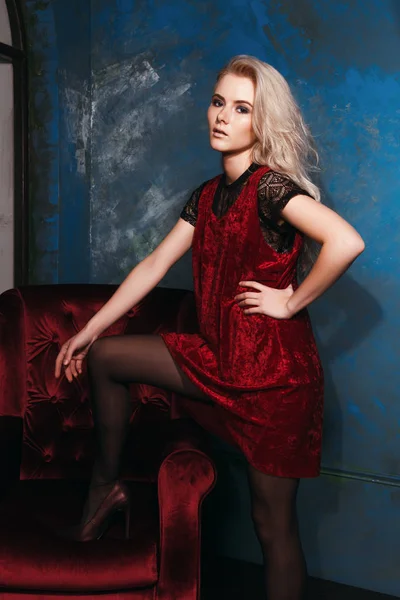 Bir sandalyede bir elbise ile poz güzel sarışın kız