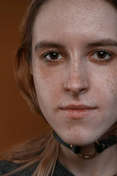 Портрет красивой девушки с веснушками в студии на коричневом фоне — стоковое фото