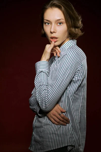 Hermosa chica con una expresión seria en su cara en el estudio sobre un fondo rojo —  Fotos de Stock