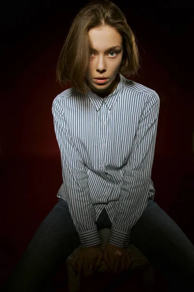 Hermosa chica con una expresión seria en su cara en el estudio sobre un fondo rojo — Foto de Stock