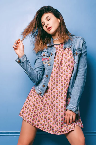 Hermosa chica positiva en una chaqueta vaqueros sobre un fondo azul sonriendo y posando —  Fotos de Stock