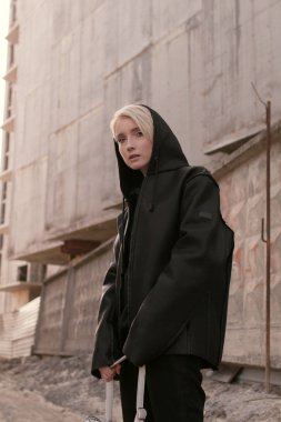 Siyah şık giysiler ve bir çanta bir kısa saç kesimi, sarışın bir kızla sokakta yürüyor