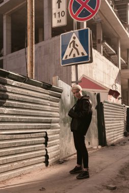 Siyah şık giysiler ve bir çanta bir kısa saç kesimi, sarışın bir kızla sokakta yürüyor