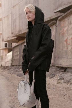 Siyah şık giysiler ve bir çanta bir kısa saç kesimi, sarışın bir kızla sokakta yürüyor
