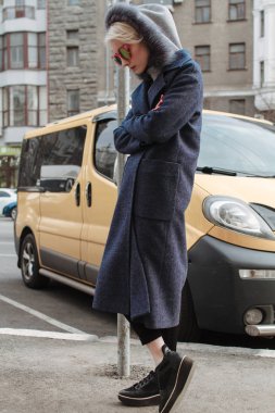 Sarışın kız gözlük ve bir kat ile şehrin sokaklarında yürüyor