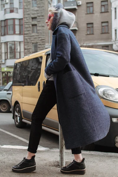 Sarışın kız gözlük ve bir kat ile şehrin sokaklarında yürüyor