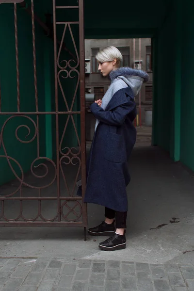 Блондинка в очках и пальто ходит по улицам города — стоковое фото