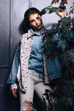 Güzel kız kot pantolon bir çiçek bir tencerede yanında poz veriyor