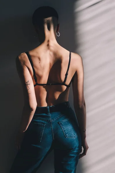 Attraktiv tjej med perfekt kropp och kort hår poserar i jeans i solljus — Stockfoto