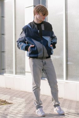 Moda giysiler içinde bir genç ve şık adam şehirde sokakta yürüyor