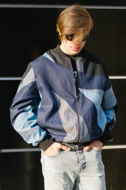 Moda giysiler içinde bir genç ve şık adam şehirde sokakta yürüyor