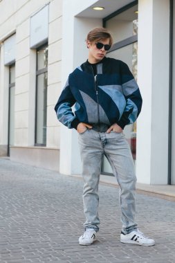 Moda giysiler içinde bir genç ve şık adam şehirde sokakta yürüyor