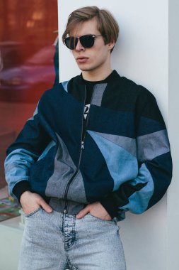 Moda giysiler içinde bir genç ve şık adam şehirde sokakta yürüyor