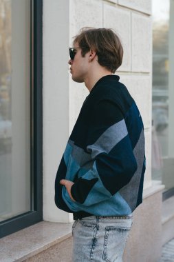 Moda giysiler içinde bir genç ve şık adam şehirde sokakta yürüyor
