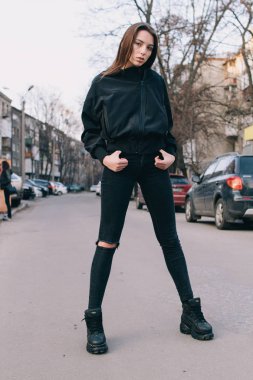 Genç ve şık bir kız moda giysiler içinde şehirde sokakta yürüyor