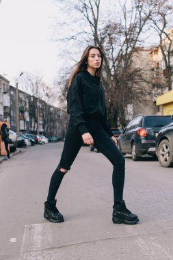 Genç ve şık bir kız moda giysiler içinde şehirde sokakta yürüyor