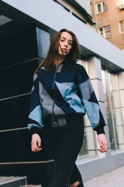 Genç ve şık bir kız moda giysiler içinde şehirde sokakta yürüyor