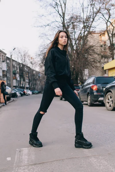 Uma menina jovem e elegante em roupas da moda caminha pela rua na cidade — Fotografia de Stock