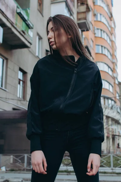 Uma menina jovem e elegante em roupas da moda caminha pela rua na cidade — Fotografia de Stock