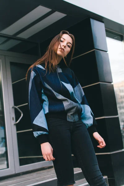 Uma menina jovem e elegante em roupas da moda caminha pela rua na cidade — Fotografia de Stock