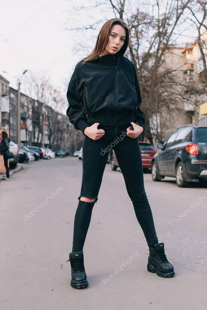 A young and stylish girl in fashionable clothes walks down the street in the city