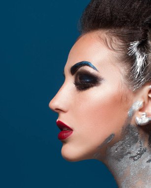 Mavi bir arka plan üzerinde yaratıcı makyajlı kız