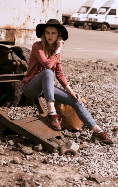 Bir kız bir şapka ve şık giysiler sokakta yürüyor 