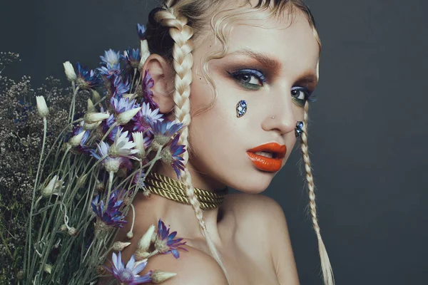 Portrait féminin à la mode en studio avec cheveux, maquillage et fleurs — Photo
