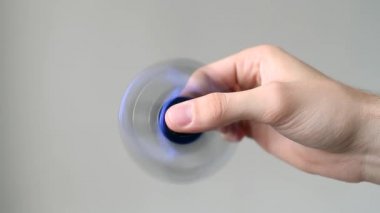 Bir erkek eli beyaz zemin üzerinde bir spinner oynuyor